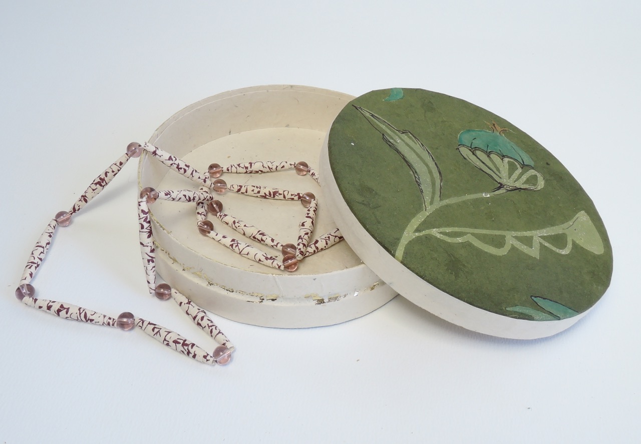 Kleine runde Schmuckdose mit handgearbeiteten Blumenmotiv und einer Kette aus Papier