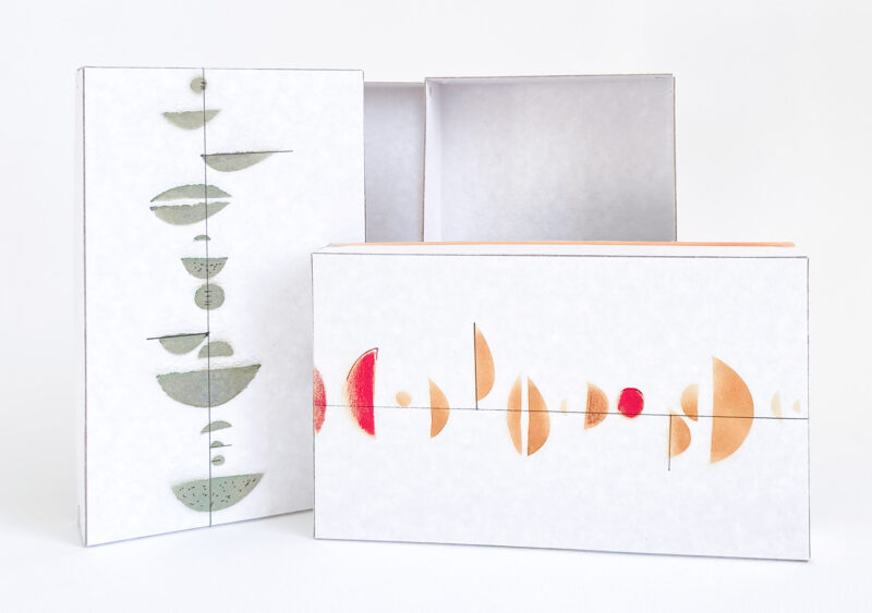 Zwei Schachtel aus weisser Pappe mit farbigen Druckmotiven